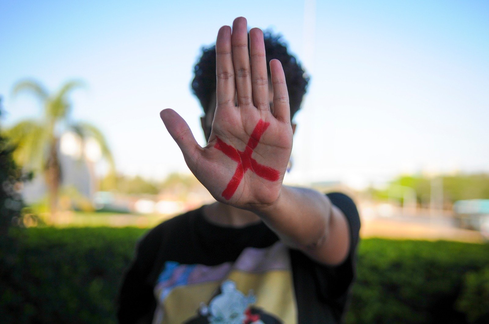 Pessoa mostra a palma da mão com um X vermelho pintado, símbolo da campanha contra a violência doméstica