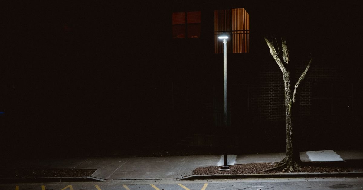 Calçada vazia iluminada por um poste de luz durante a noite em rua residencial