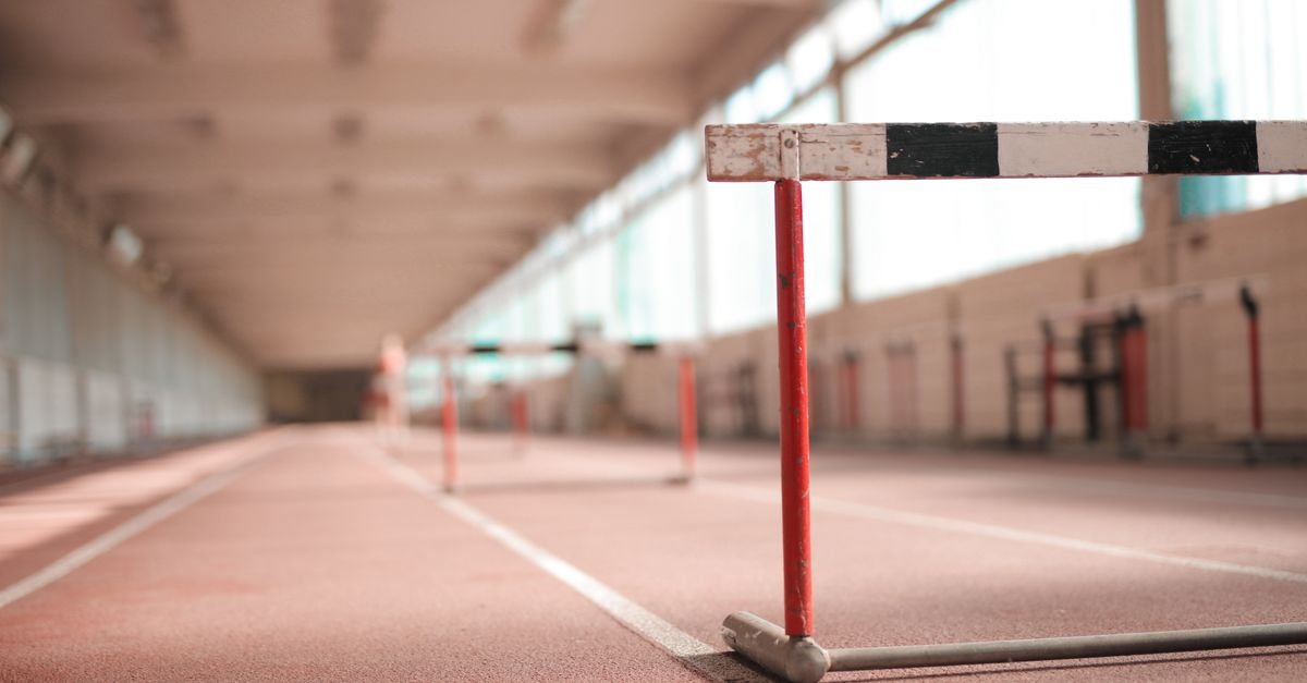 Barreira de atletismo pintada de branco, preto e vermelho em pista coberta