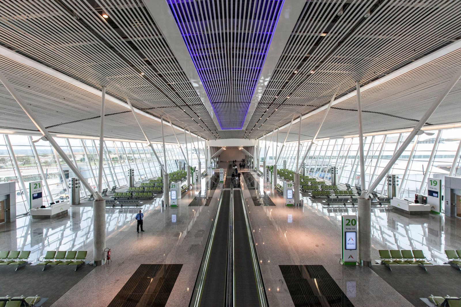 Saguão de embarque do Aeroporto Internacional de Brasília, com esteira rolante, poltronas e placas dos portões 19, 20 e 21