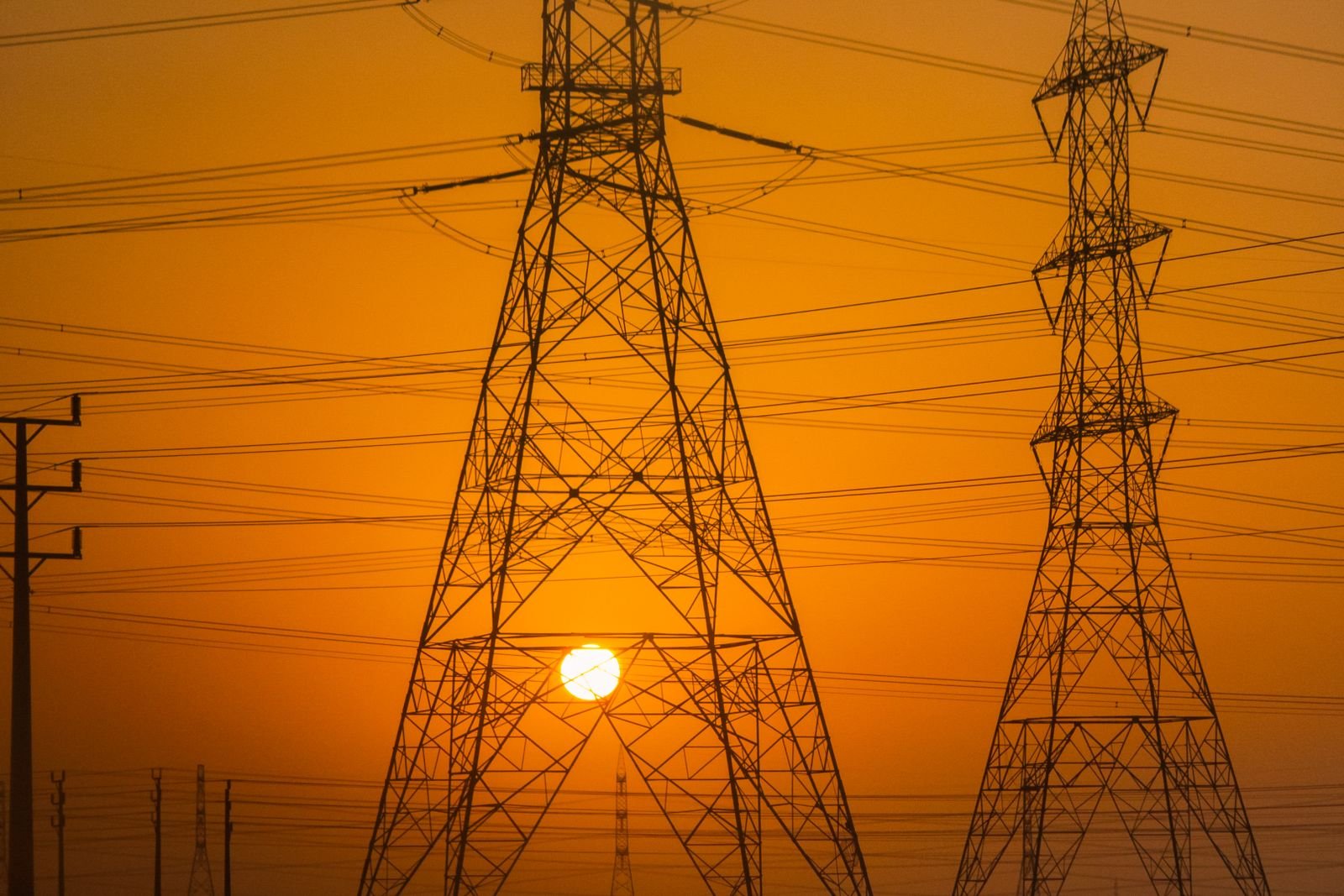 Torres de transmissão de energia em silhueta contra o pôr do sol, imagem de arquivo