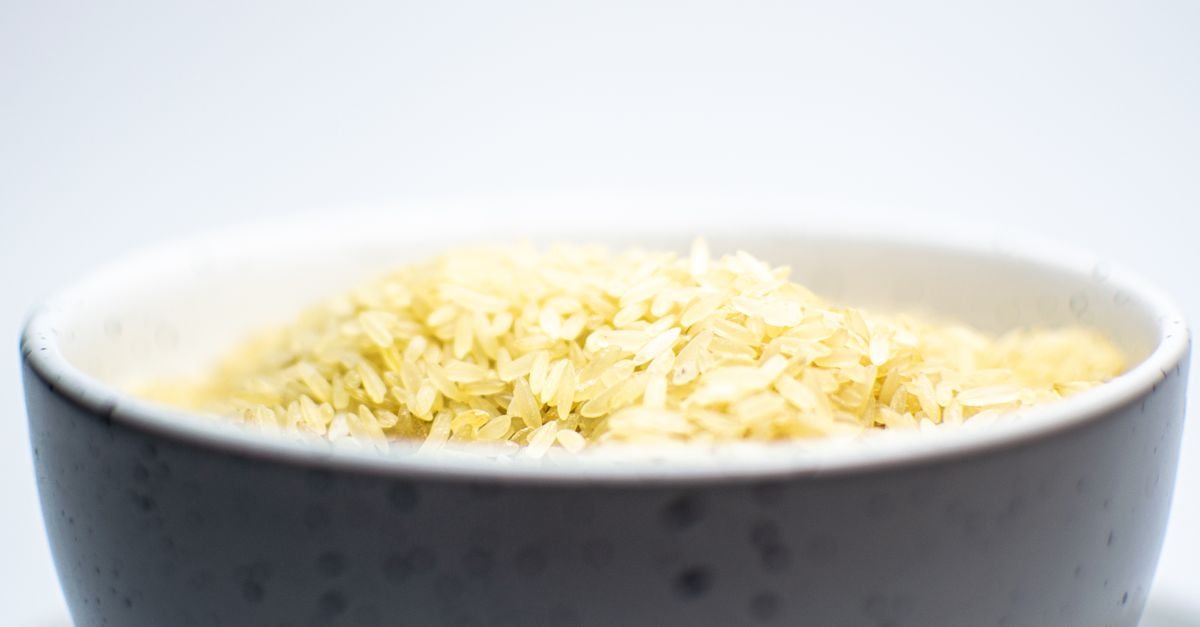 Close-up de grãos de arroz cru em uma tigela de cerâmica sobre fundo claro
