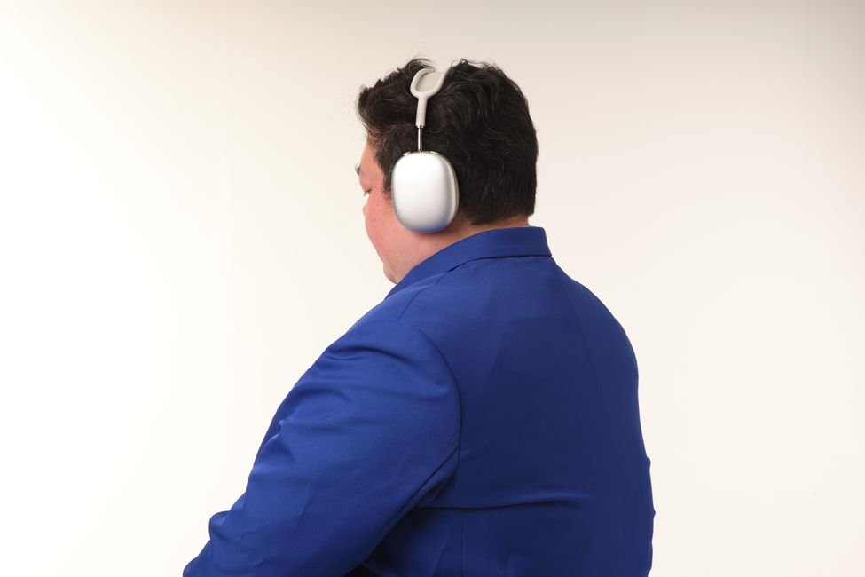 Profissional de blazer azul usando fone de ouvido abafador de ruido em ambiente de trabalho de fundo claro