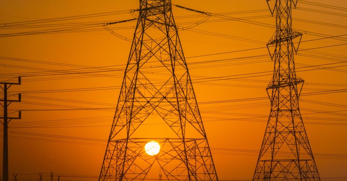 Torres de transmissão de energia elétrica em silhueta contra céu alaranjado