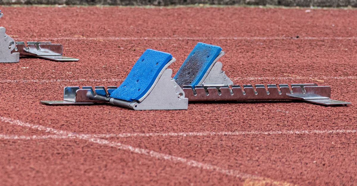 Bloco de partida azul posicionado na raia de uma pista de atletismo