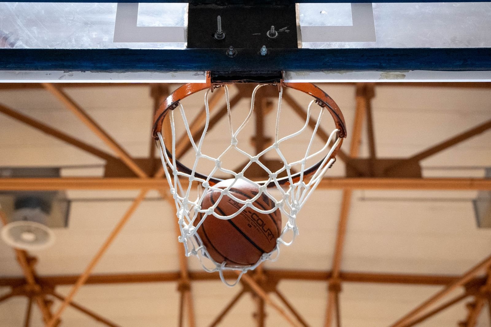 Bola de basquete passando pela cesta em um ginásio coberto