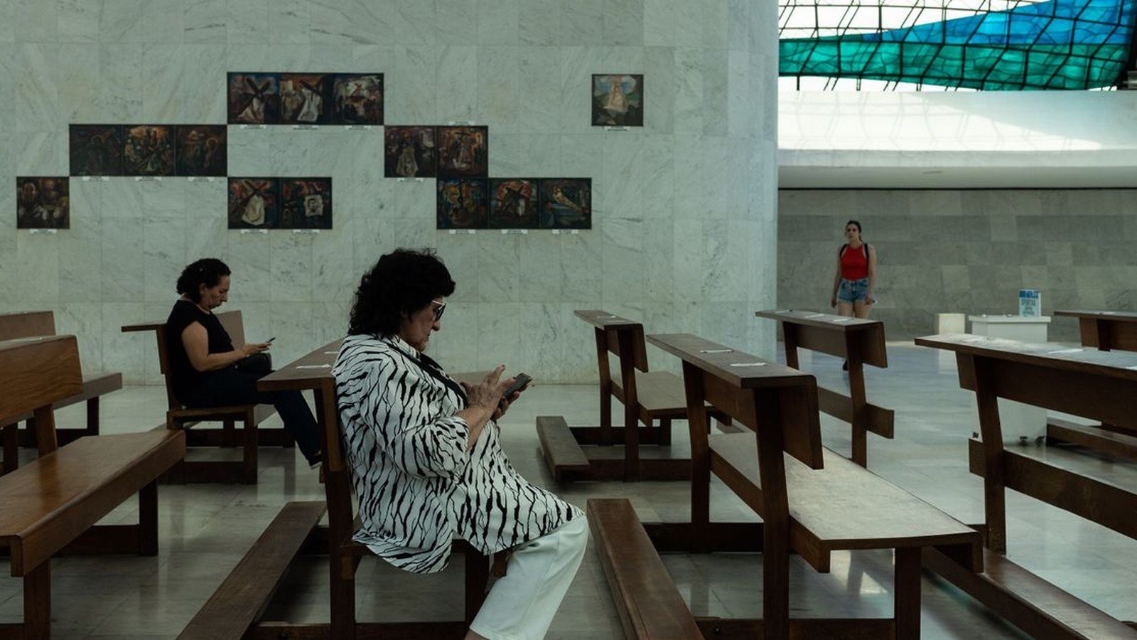 Visitantes sentados em bancos de madeira no interior da Catedral de Brasília