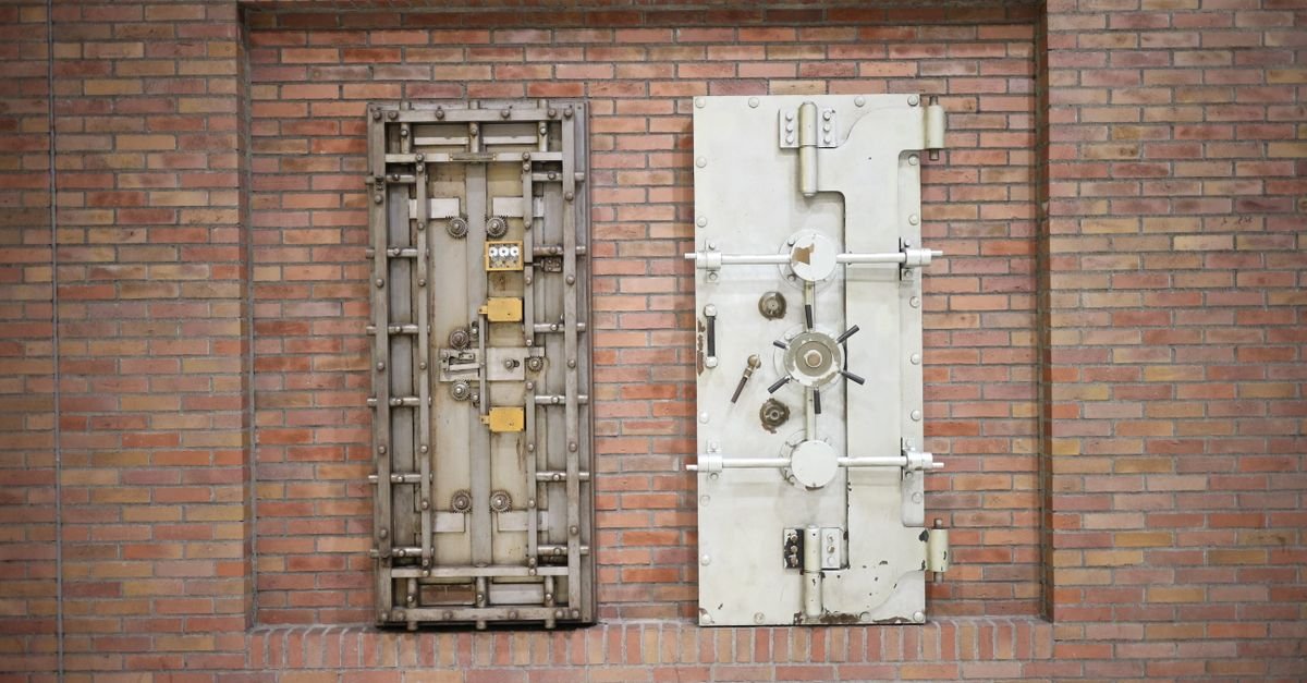 Duas portas de cofre de banco em aço embutidas em uma parede de tijolos
