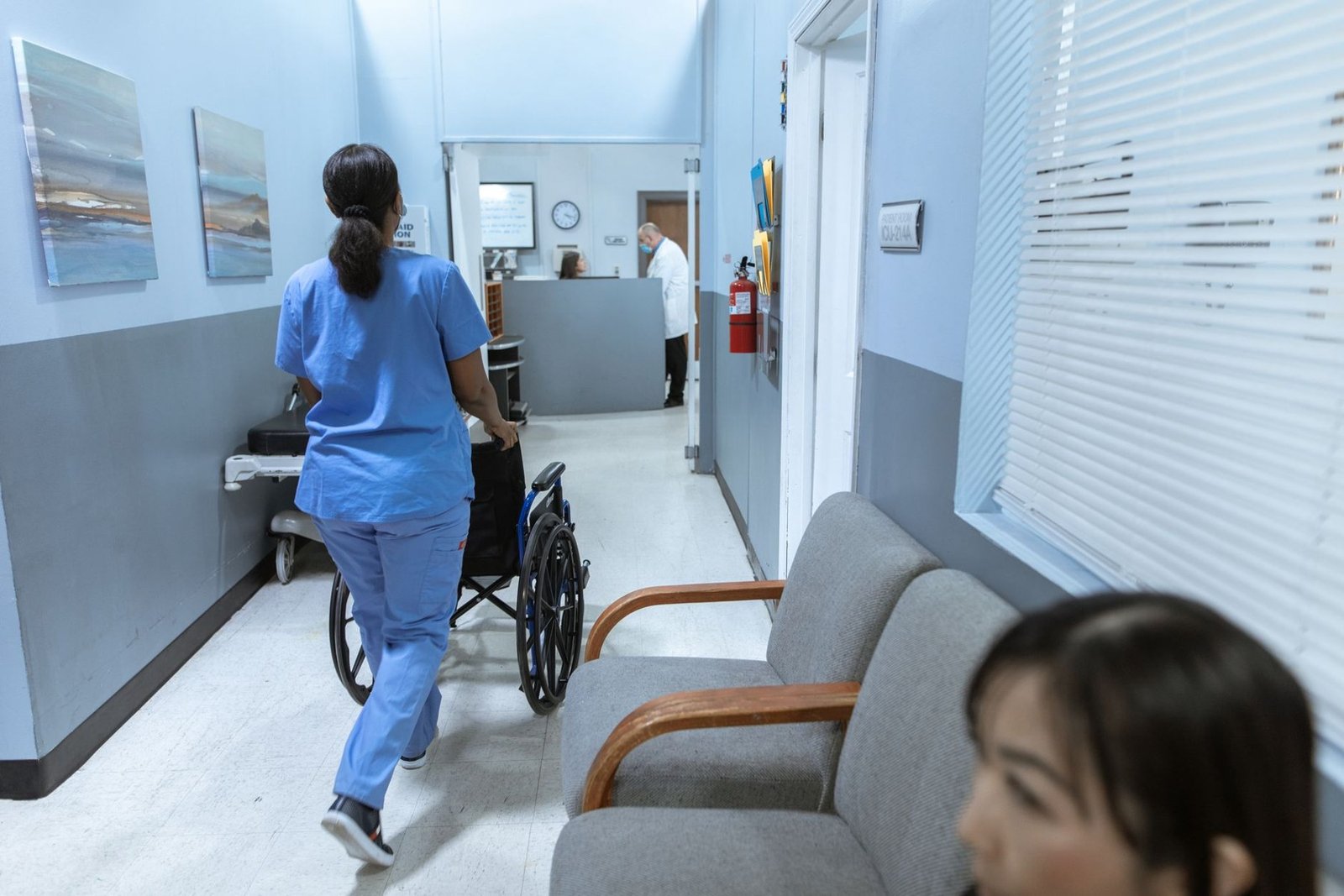 Profissional de saúde empurra uma cadeira de rodas em corredor de hospital (foto ilustrativa)