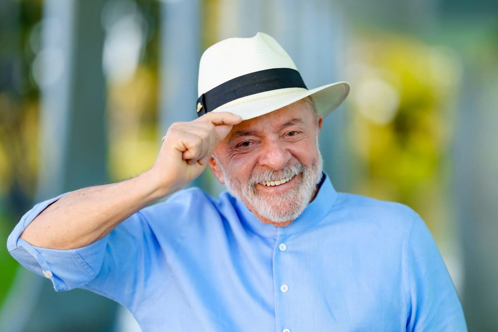 Presidente Lula sorri e toca a aba de um chapéu panamá branco, de camisa azul, em foto de julho de 2026