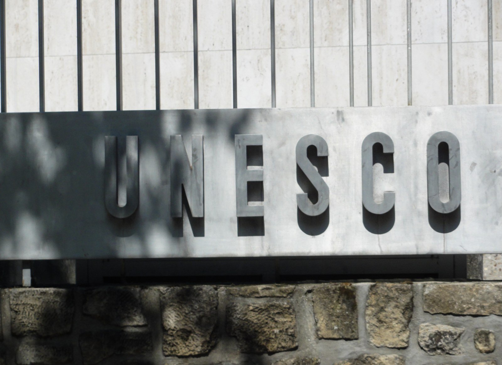 Letras em pedra com a palavra UNESCO na fachada da sede da organização, em Paris