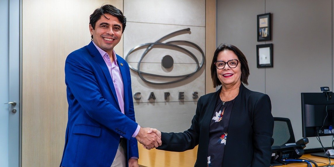 Antonio Gomes de Souza Filho e Denise Pires de Carvalho apertam as mãos diante do logotipo da Capes