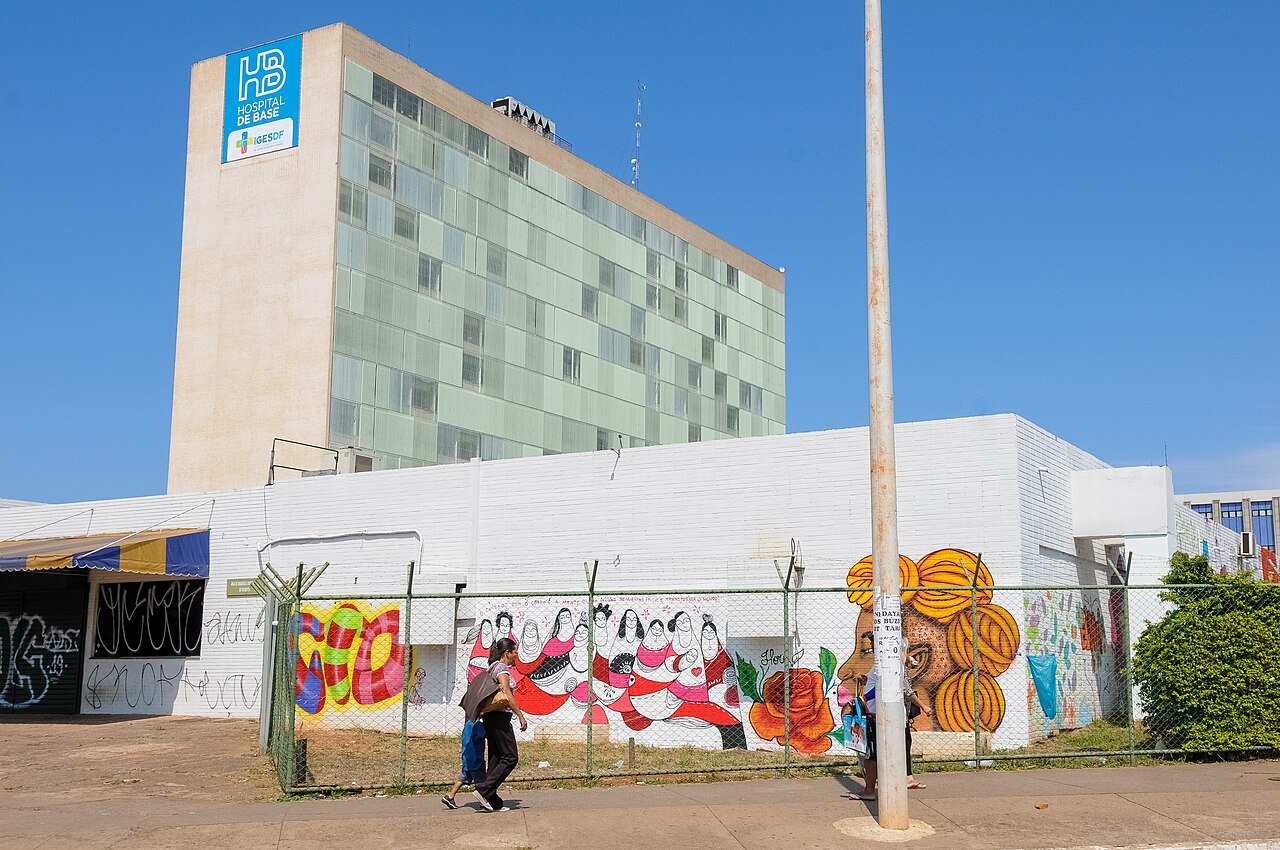 Prédio do Instituto Hospital de Base do Distrito Federal visto da rua, com muro grafitado à frente