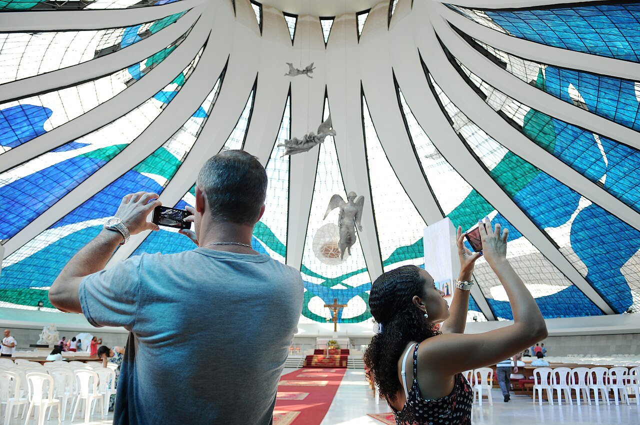 Interior da Catedral Metropolitana de Brasília, com vitrais azuis e esculturas de anjos suspensas