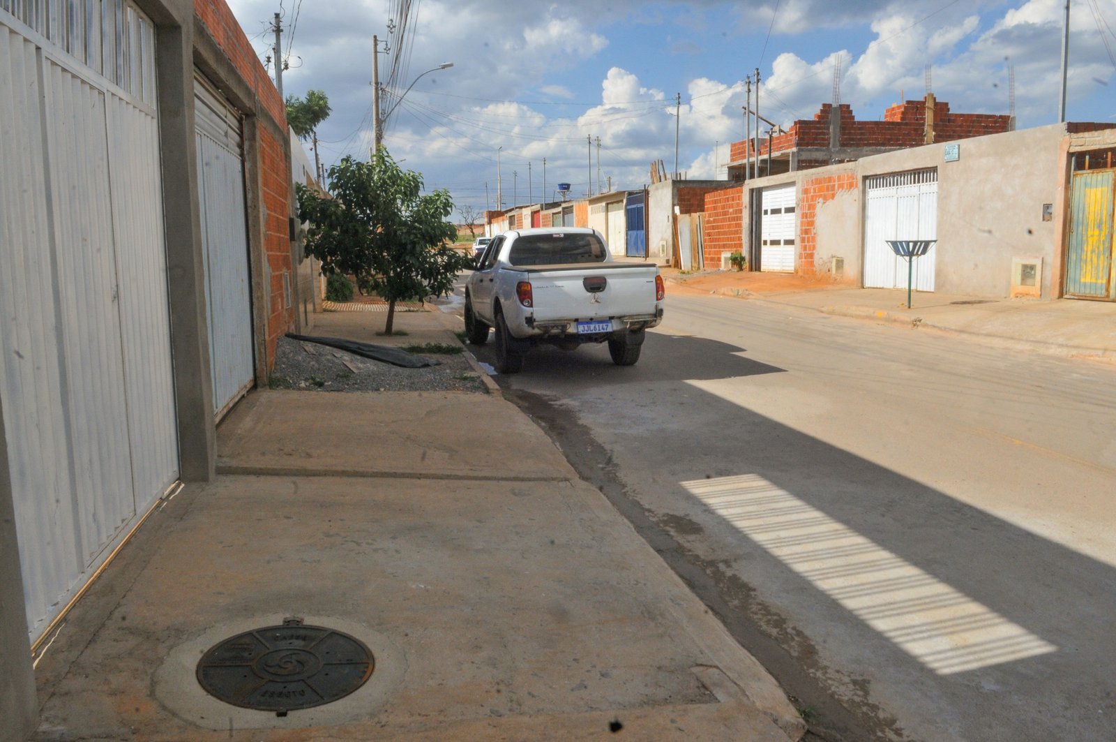 Rua de bairro do DF com tampa de poço de visita de esgoto da Caesb na calçada, em foto de arquivo de obra de rede de esgoto