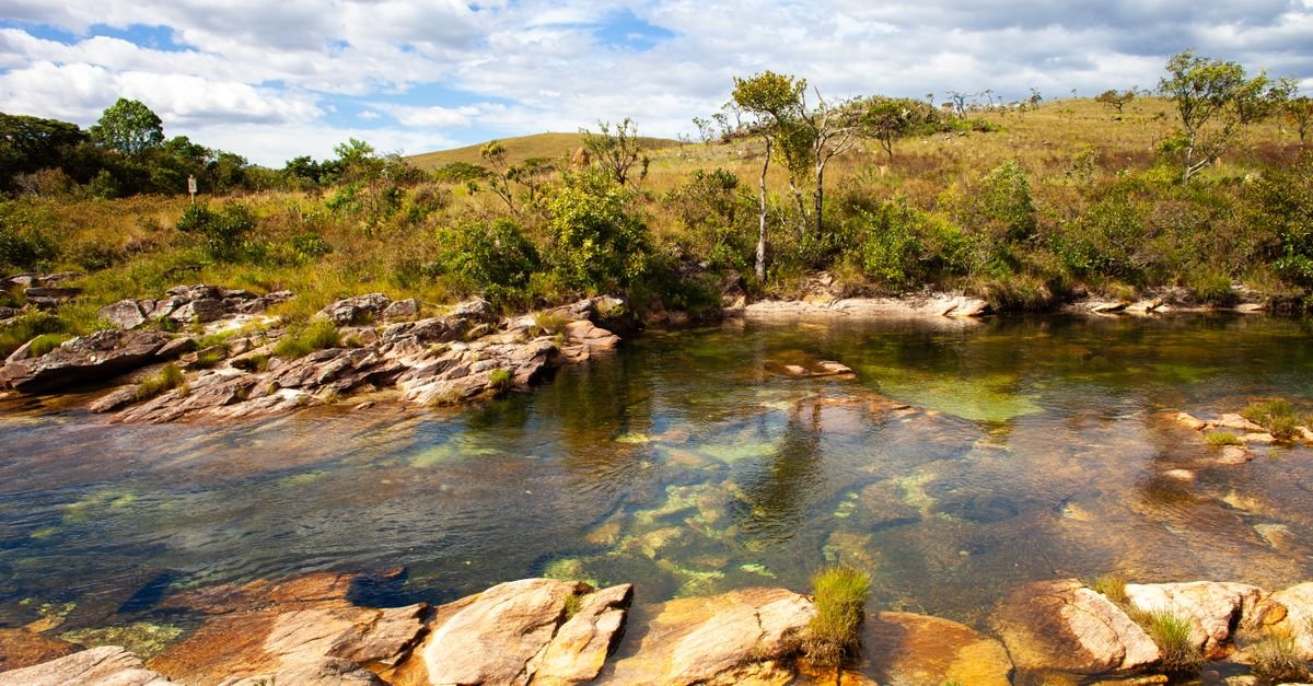 Rio de águas claras entre rochas e vegetação de savana no Cerrado brasileiro
