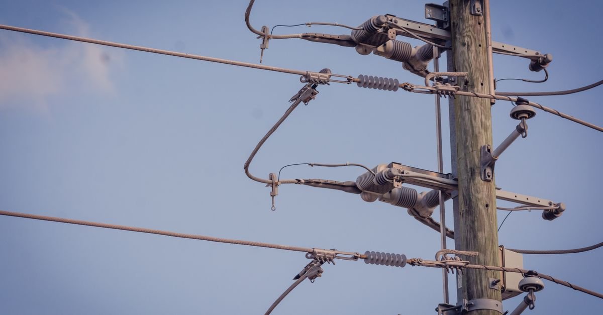 Poste de rede de distribuição de energia elétrica com cabos e isoladores contra o céu