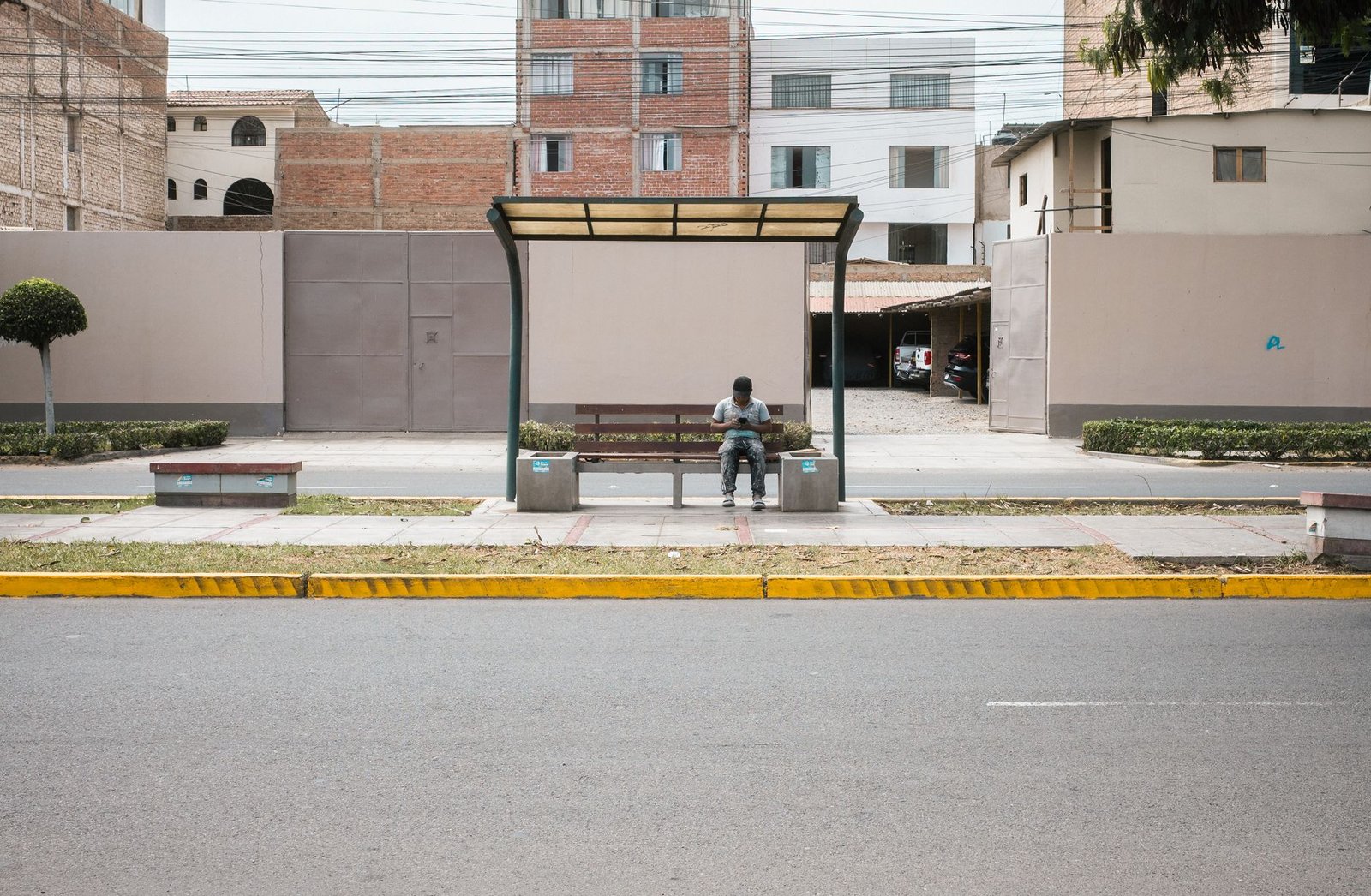 Abrigo de ônibus numa avenida com uma pessoa sentada no banco, em imagem ilustrativa de transporte coletivo