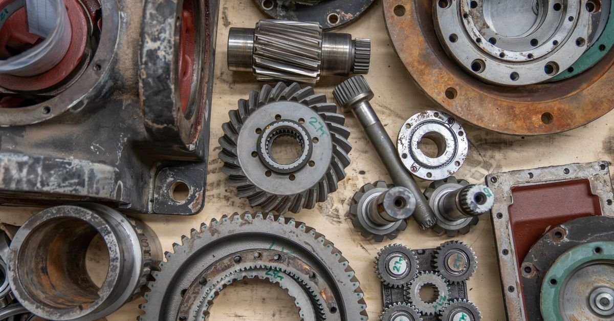 Engrenagens, eixos e peças metálicas de máquina industrial dispostos sobre bancada de oficina