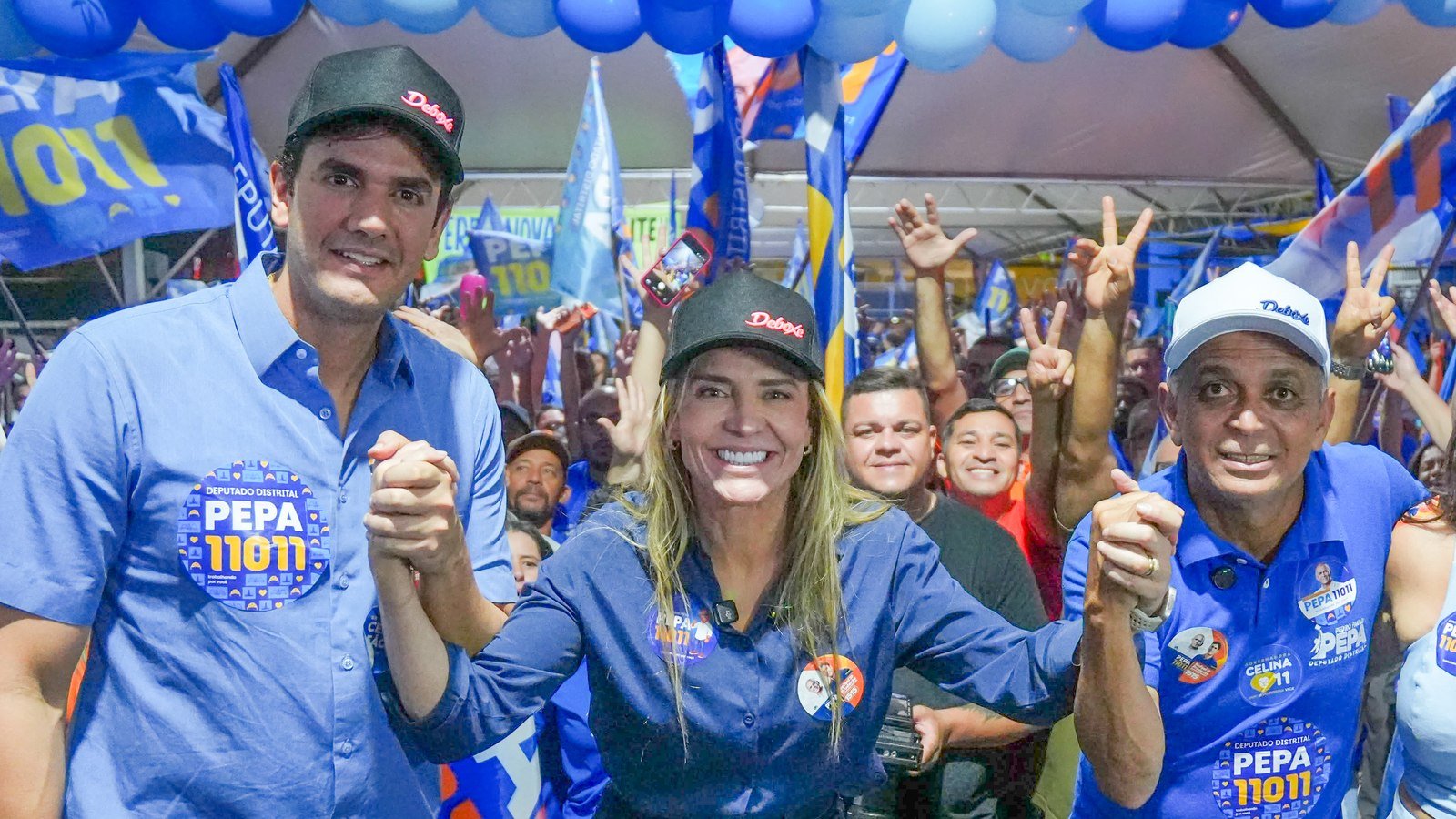 Rafael Prudente, Celina Leão e Pepa de mãos dadas no palco do comitê, na Avenida Independência, em Planaltina