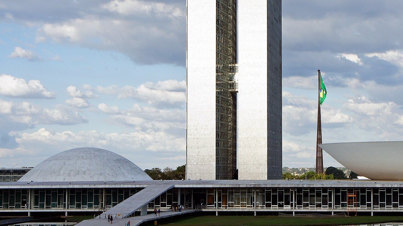 Fachada do Congresso Nacional, em Brasília, com as duas torres, a cúpula do Senado e a bandeira do Brasil