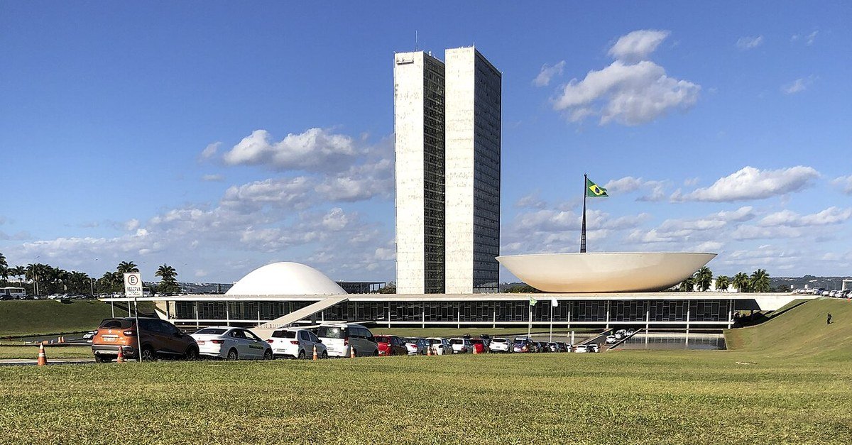 Fachada do Congresso Nacional, em Brasília, vista do gramado, com a bandeira do Brasil hasteada