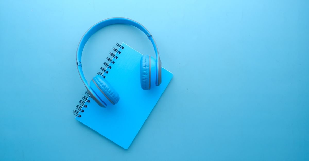 Fone de ouvido apoiado sobre caderno espiral azul