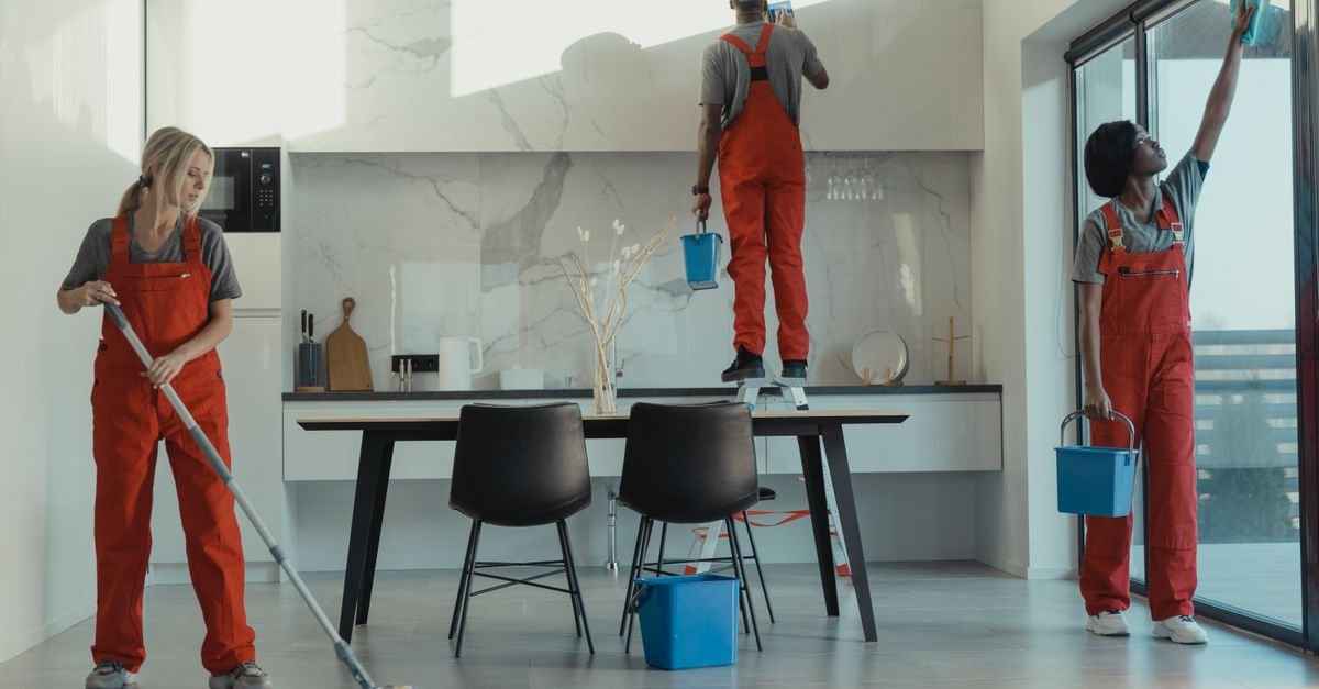 Equipe de limpeza com uniforme vermelho trabalhando em ambiente interno