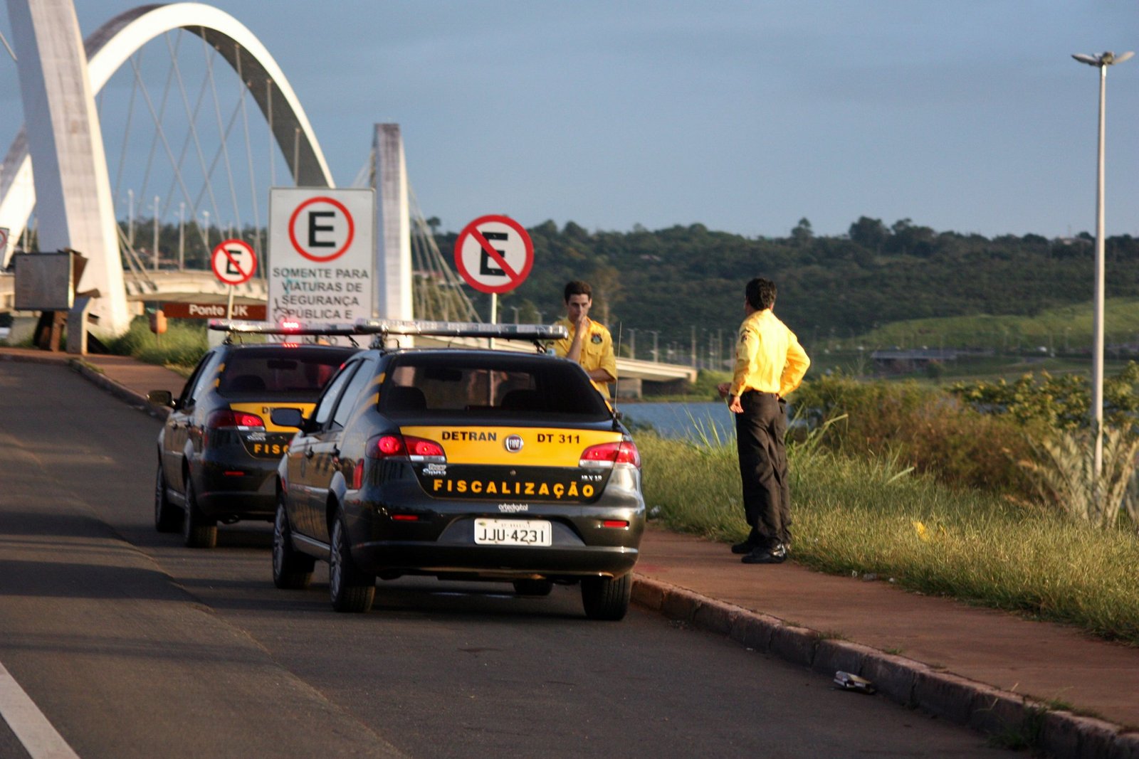 Viaturas de fiscalização do Detran-DF paradas à margem de pista, com a Ponte JK ao fundo, em Brasília