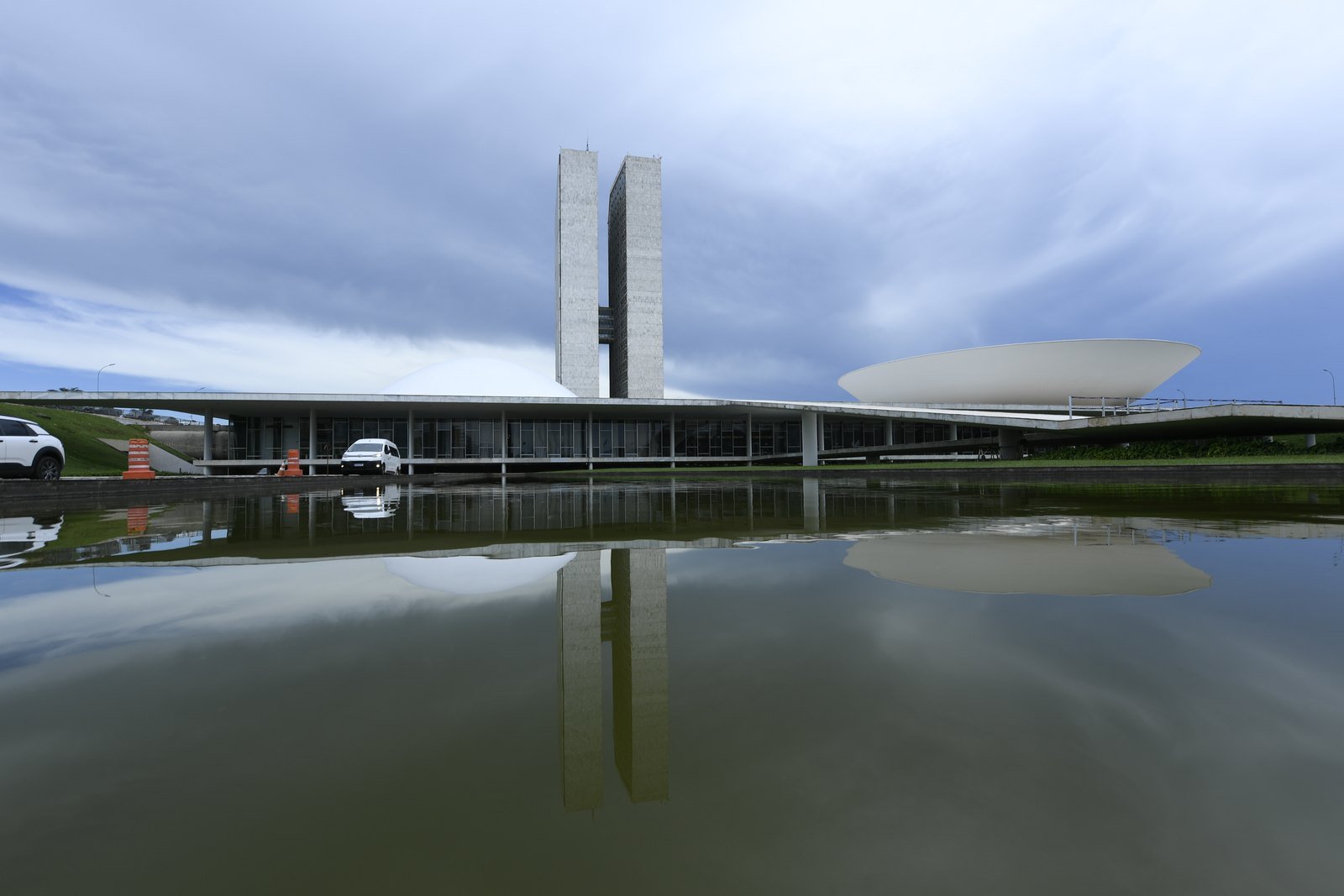 Fachada do Congresso Nacional em Brasília, com as duas torres e as cúpulas do Senado e da Câmara refletidas no espelho d'água