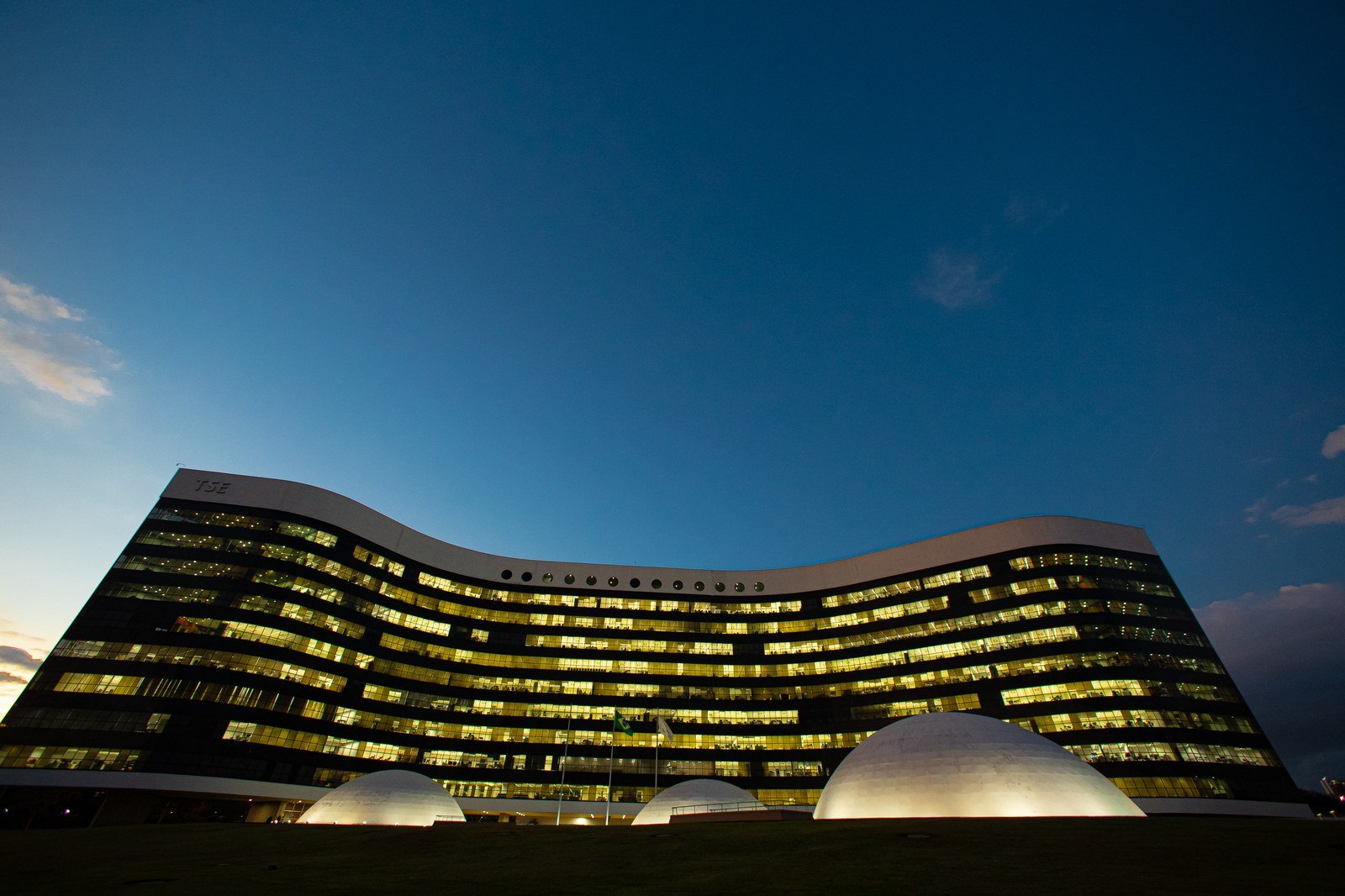 Fachada curva do prédio do Tribunal Superior Eleitoral, em Brasília, iluminada ao entardecer