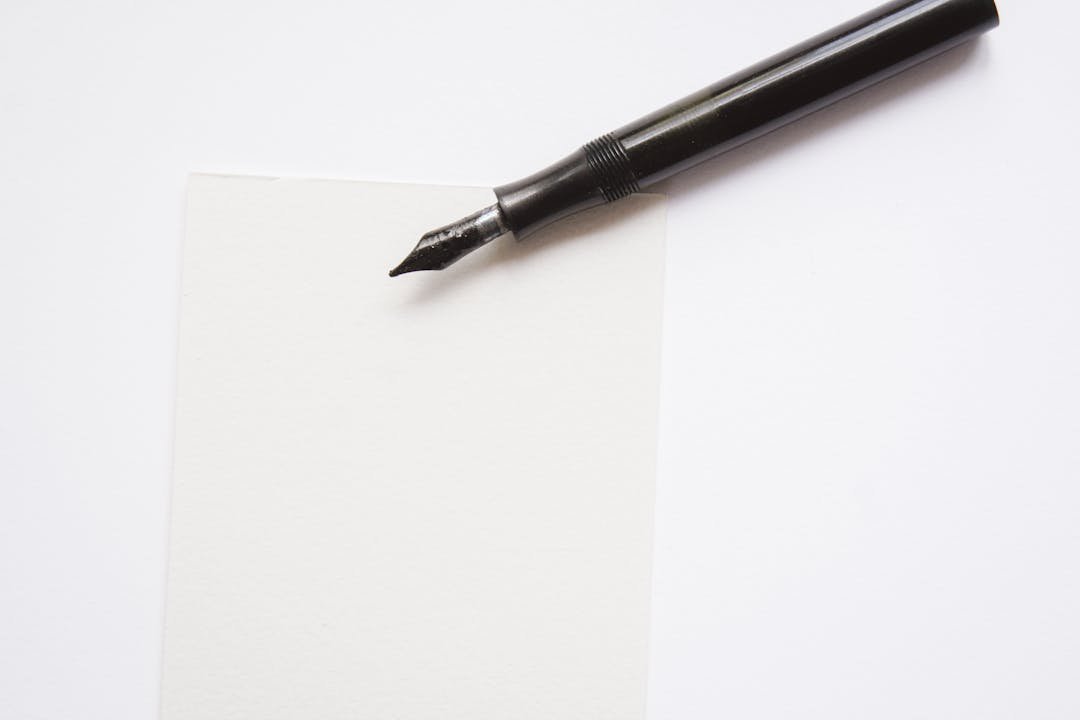 Caneta tinteiro preta sobre folha de papel branco em ambiente claro