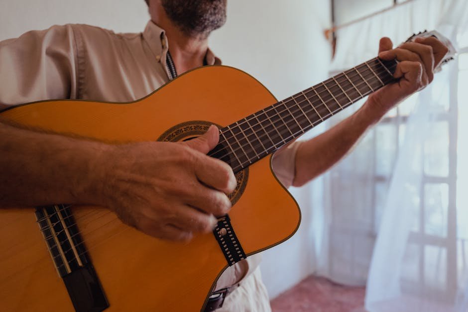 Mãos masculinas tocando violão acústico em close