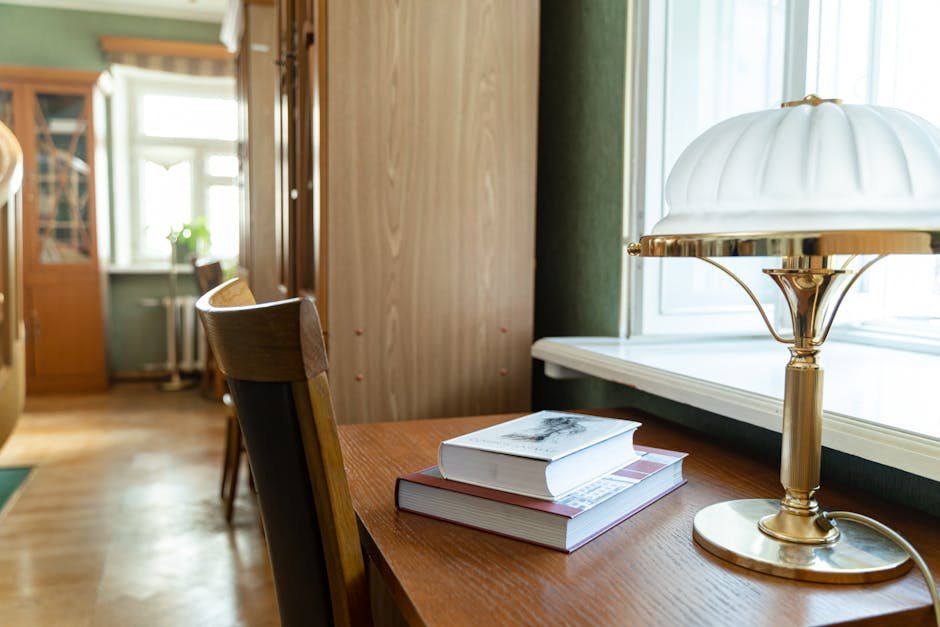 Mesa de estudo com livros empilhados e luminária acesa
