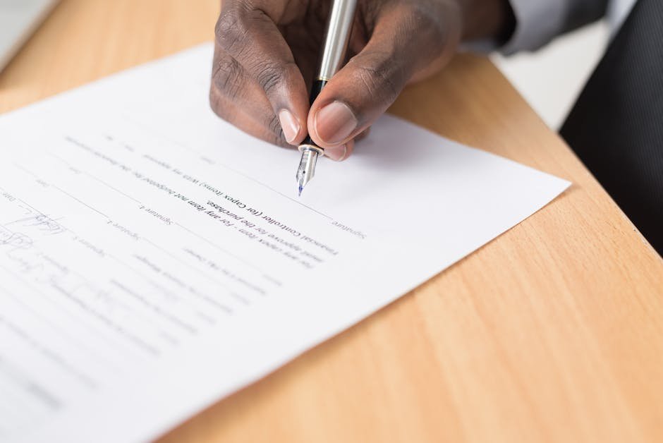 Mão assinando documento com caneta tinteiro sobre mesa de escritório
