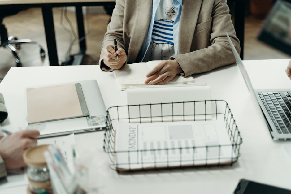 Profissional escrevendo em caderno sobre mesa de escritório