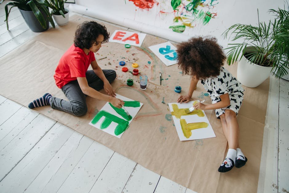 Crianças pintando letras coloridas sobre papel em chão branco
