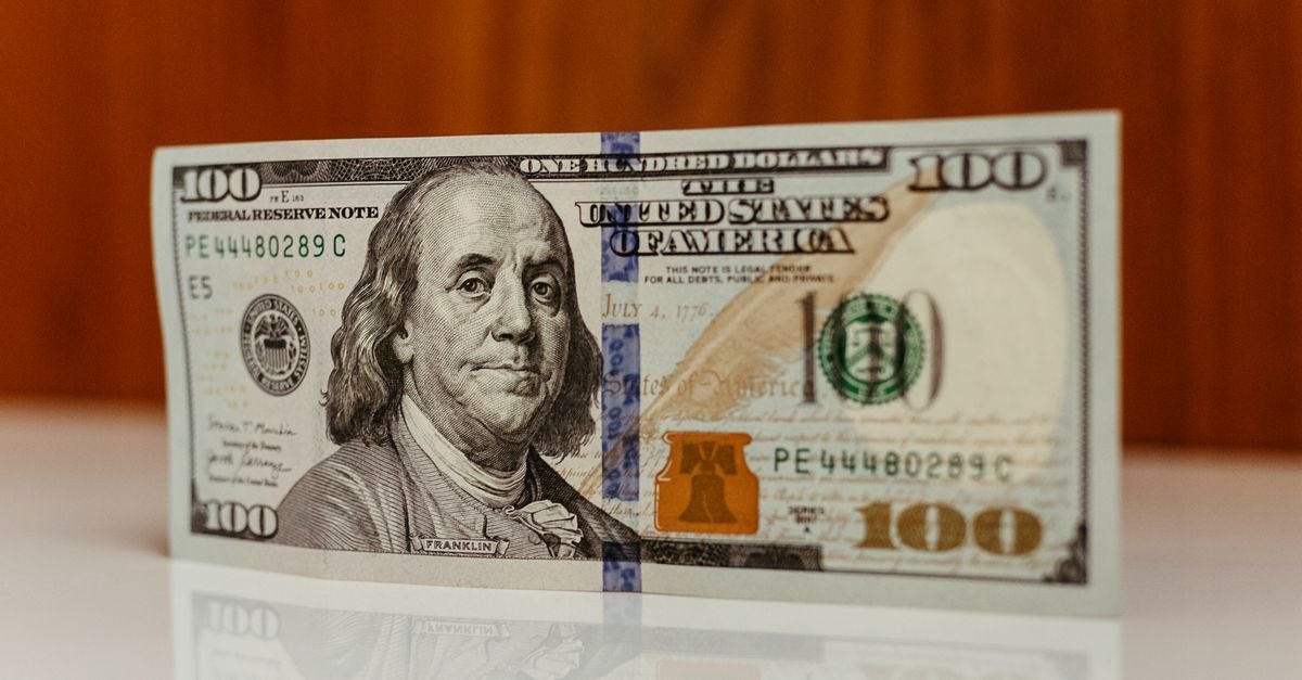 Cédula de cem dólares norte-americanos apoiada sobre superfície clara