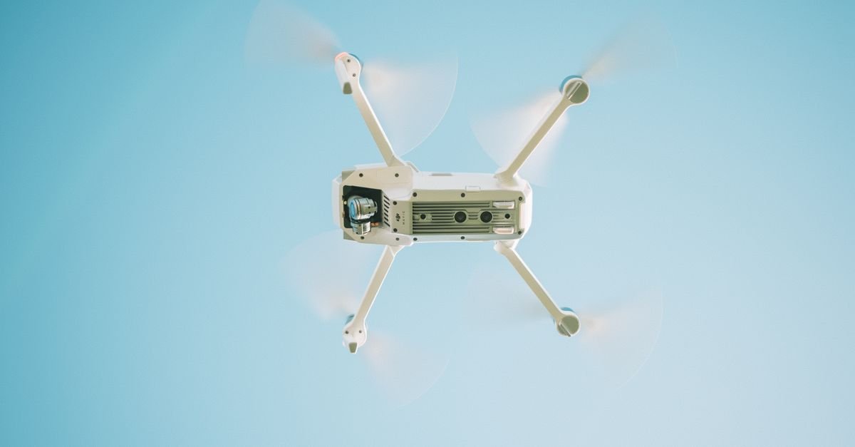 Drone branco em voo contra o céu azul