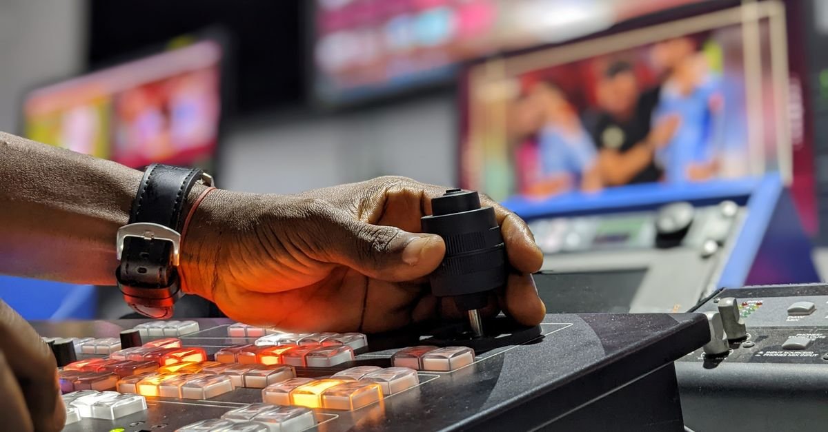 Mão acionando mesa de corte de vídeo em estúdio de televisão