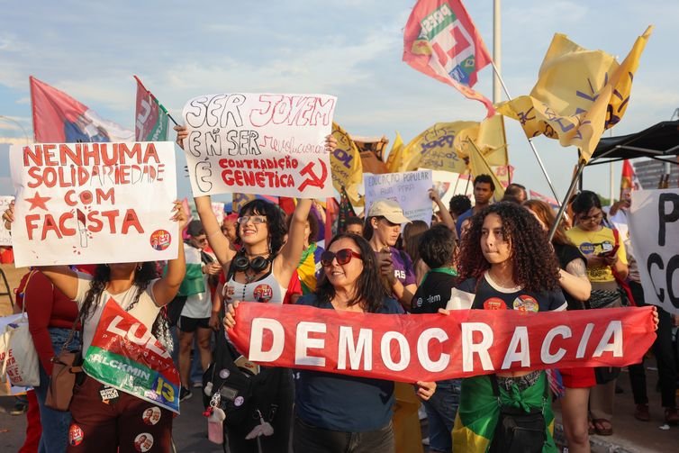 Jovens seguram faixa com a palavra Democracia e cartazes durante o ato na Esplanada
