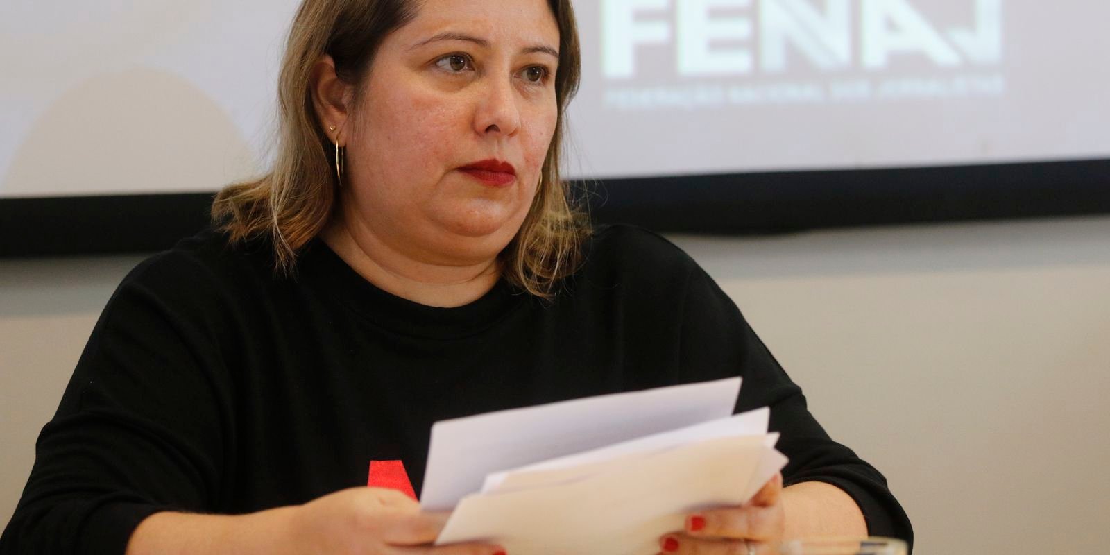 Dirigente da Fenaj fala em entrevista coletiva com o logotipo da federação projetado ao fundo