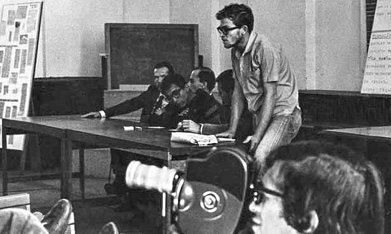 Honestino Guimarães em pé durante assembleia estudantil, em foto histórica em preto e branco