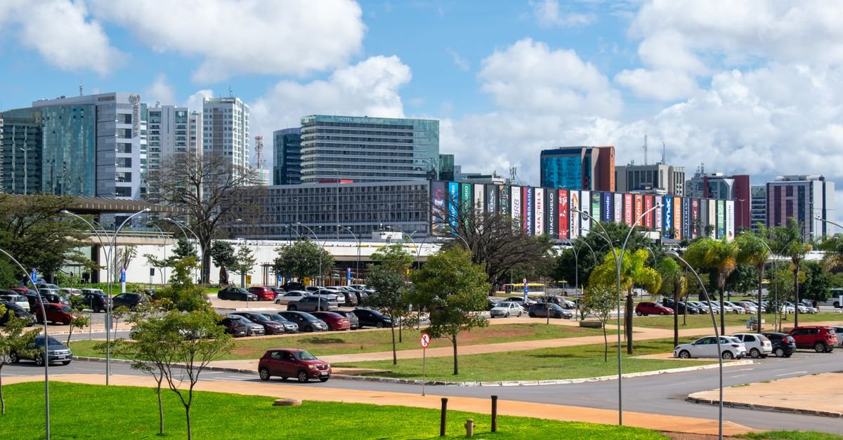 Vista de prédios e avenida em Brasília sob céu com nuvens