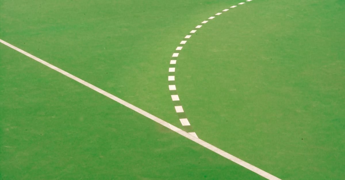 Linhas brancas demarcadas sobre a grama verde de um campo de futebol