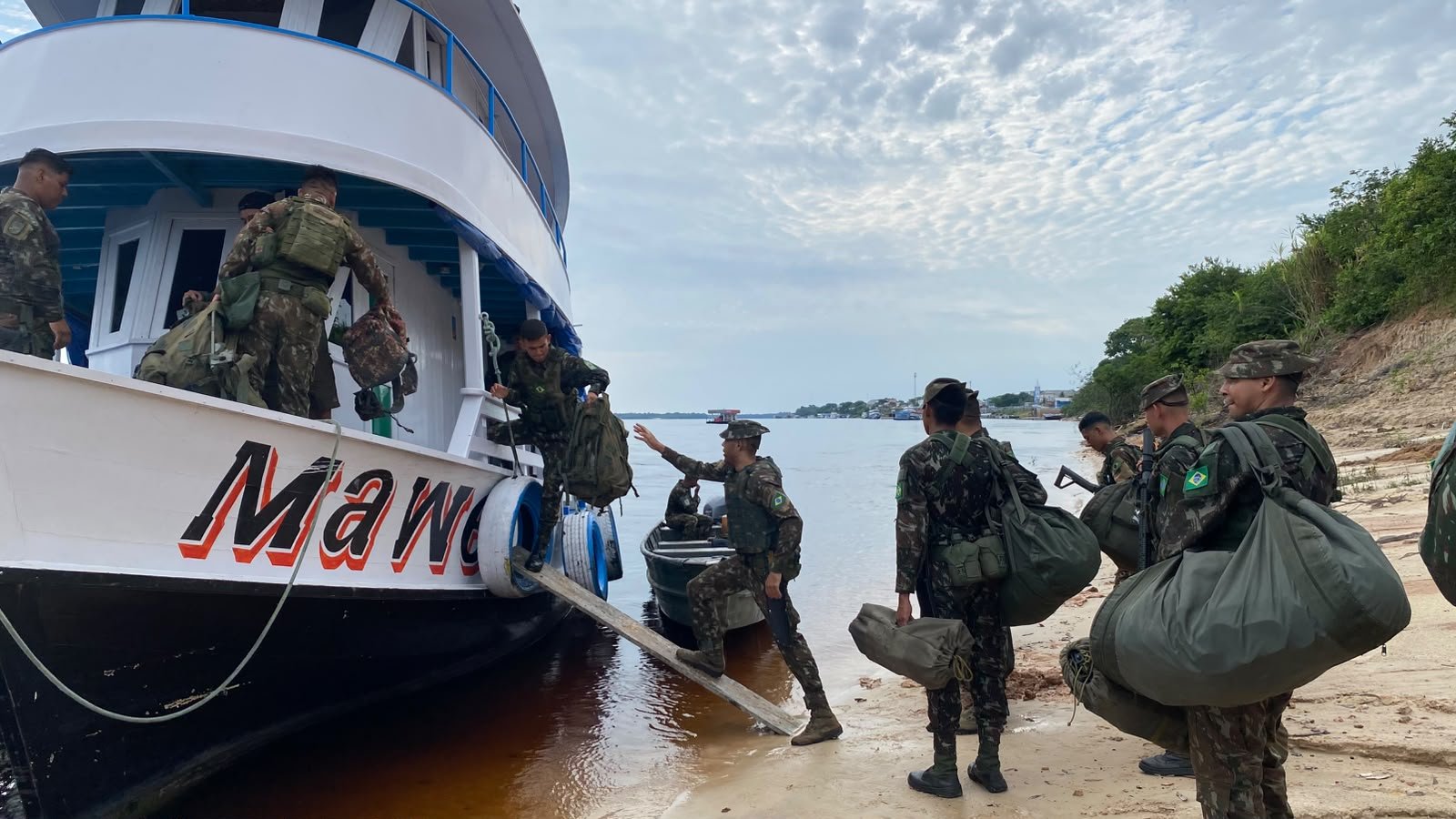 Militares do Exército embarcam com mochilas em um barco na margem de um rio da Amazônia para apoiar a votação do segundo turno