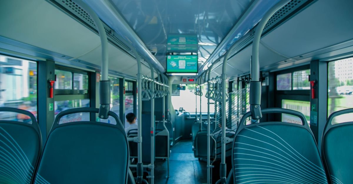 Interior de ônibus urbano vazio, com bancos e barras de apoio