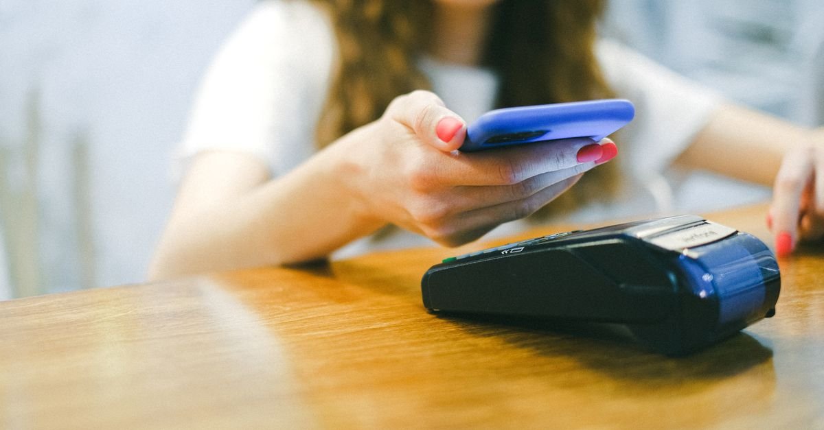 Pessoa faz pagamento por aproximação com o celular em uma maquininha de cartão
