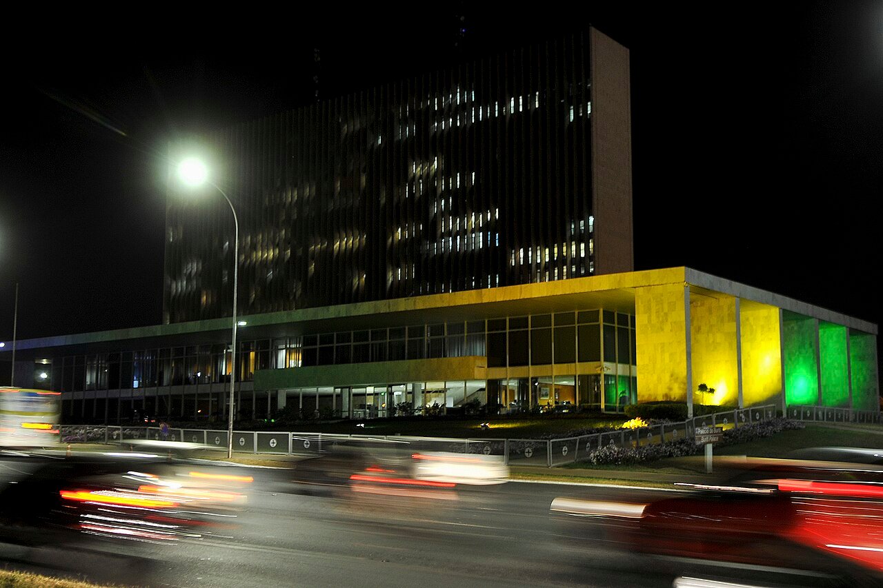 Fachada do Palácio do Buriti, sede do governo do Distrito Federal, iluminada à noite, com carros passando na via em frente