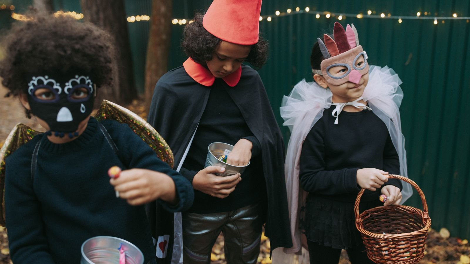 Crianças fantasiadas de Halloween segurando baldinho de doces